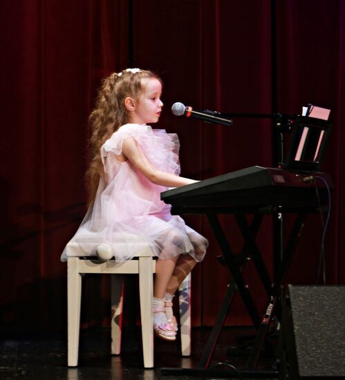 Dziewczynka w białej sukience grająca na pianinie