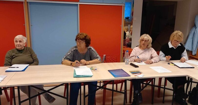 Seniorzy siedzą za stołami