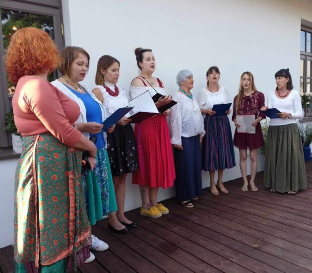 Grupa kobiet śpiewająca na drewnianym podeście