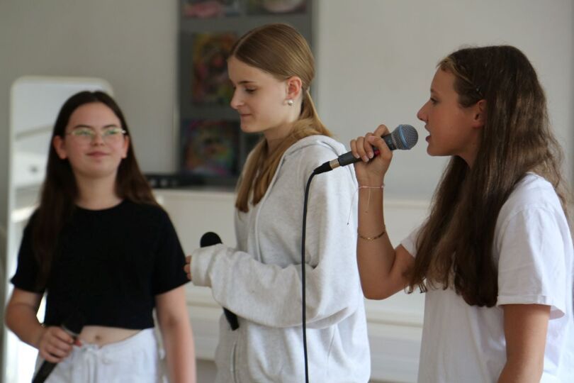 Zdjęcie: trzy dziewczyny z mikrofonami w ręce, jedna śpiewająca