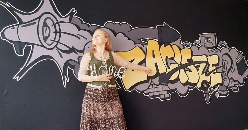 Zdjęcie: Uśmiechnięta blondynka, w średnim wieku, w boho stroju, na tle graffiti Zacisze