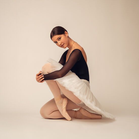 Zdjęcie: młoda tancerka w czarnej obcisłej bluzce i białej, krótkiej spódnicy