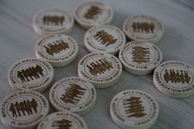 Zdjęcie: pamiątkowe drewniaczki dla uczestników gry terenowej z napisem Małe Historie Wielkich Kobiet i geocaching