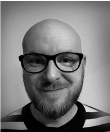 Zdjęcie: mężczyzna w okularach z lekkim zarostem w bluzce w paski