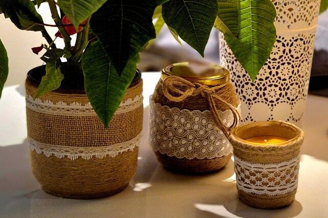 Zdjęcie: świecznik ozdobiony jutą i koronką na tle doniczki i słoika udekorowanych jutą