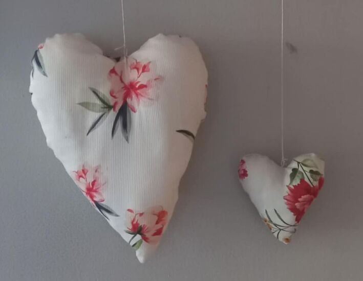 Zdjęcie dwóch białych materiałowych serduszek z elementami różowych kwiatów