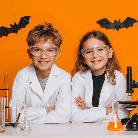 Zdjęcie: chłopiec i dziewczynka w białych fartuchach na pomarańczowym tle z dwoma nietoperzami