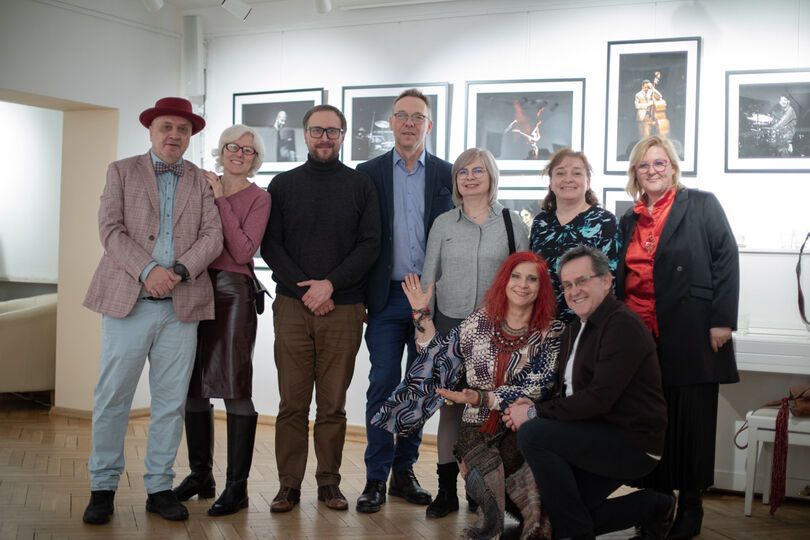 Zdjęcie: grupa uśmiechniętych osób na tle zdjęć