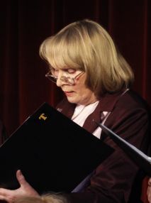 Zdjęcie kobiety w średnim wieku trzymającej teczkę z nutami