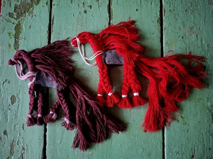 Zdjęcie: Dwie prace wykonane ze sznurka w czerwonym i bordowym kolorze na drewnianych deskach w pistacjowym kolorze