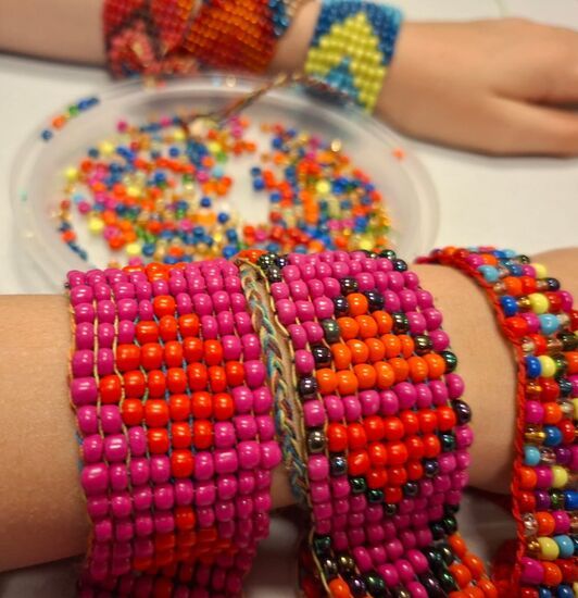 Zdjęcie: trzy koralikowe bransoletki na ręku, w odcieniach różu i czerwieni