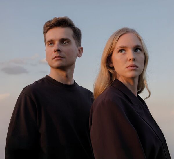 Zdjęcie: młoda kobieta w blond włosach i młody mężczyzna, wpatrzeni w ten sam kierunek, nad nimi jasne niebo